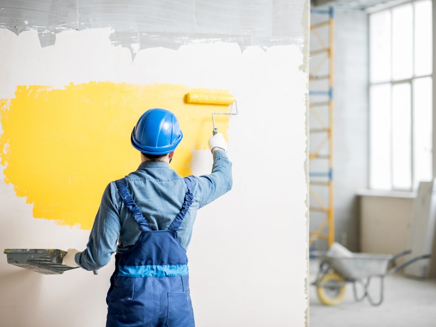Decorator rolling paint on a prepared wall